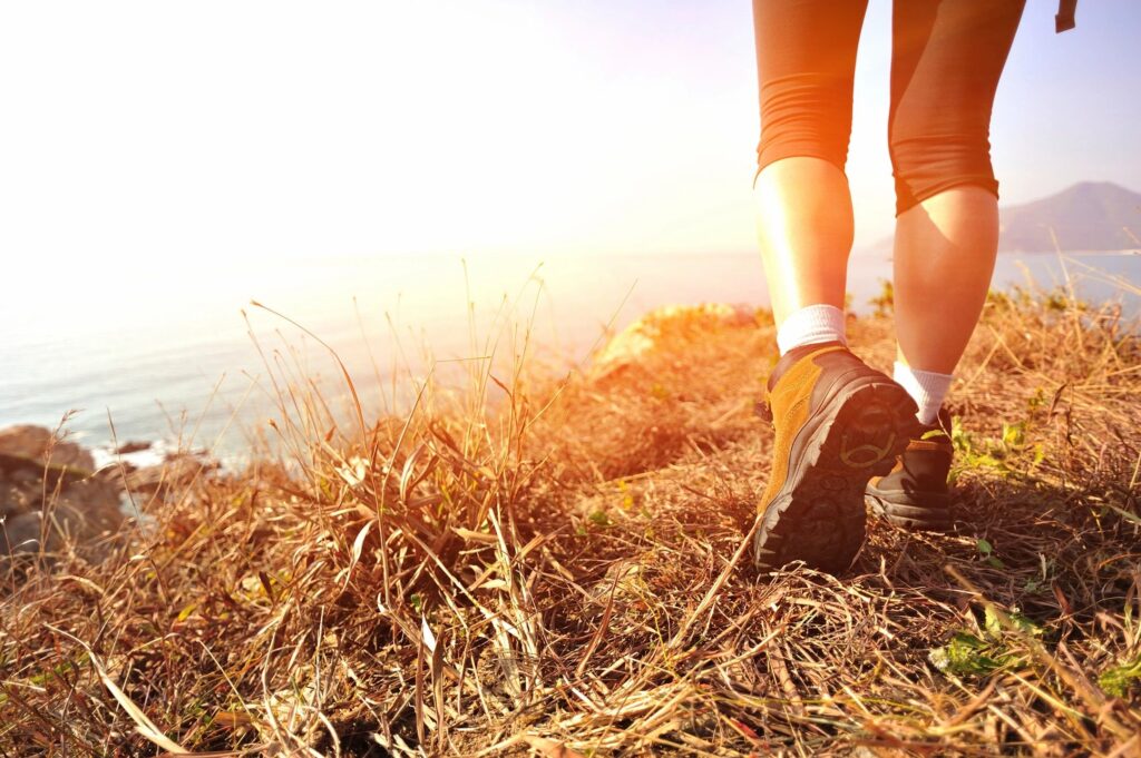 person walking on grass with sunshine in background